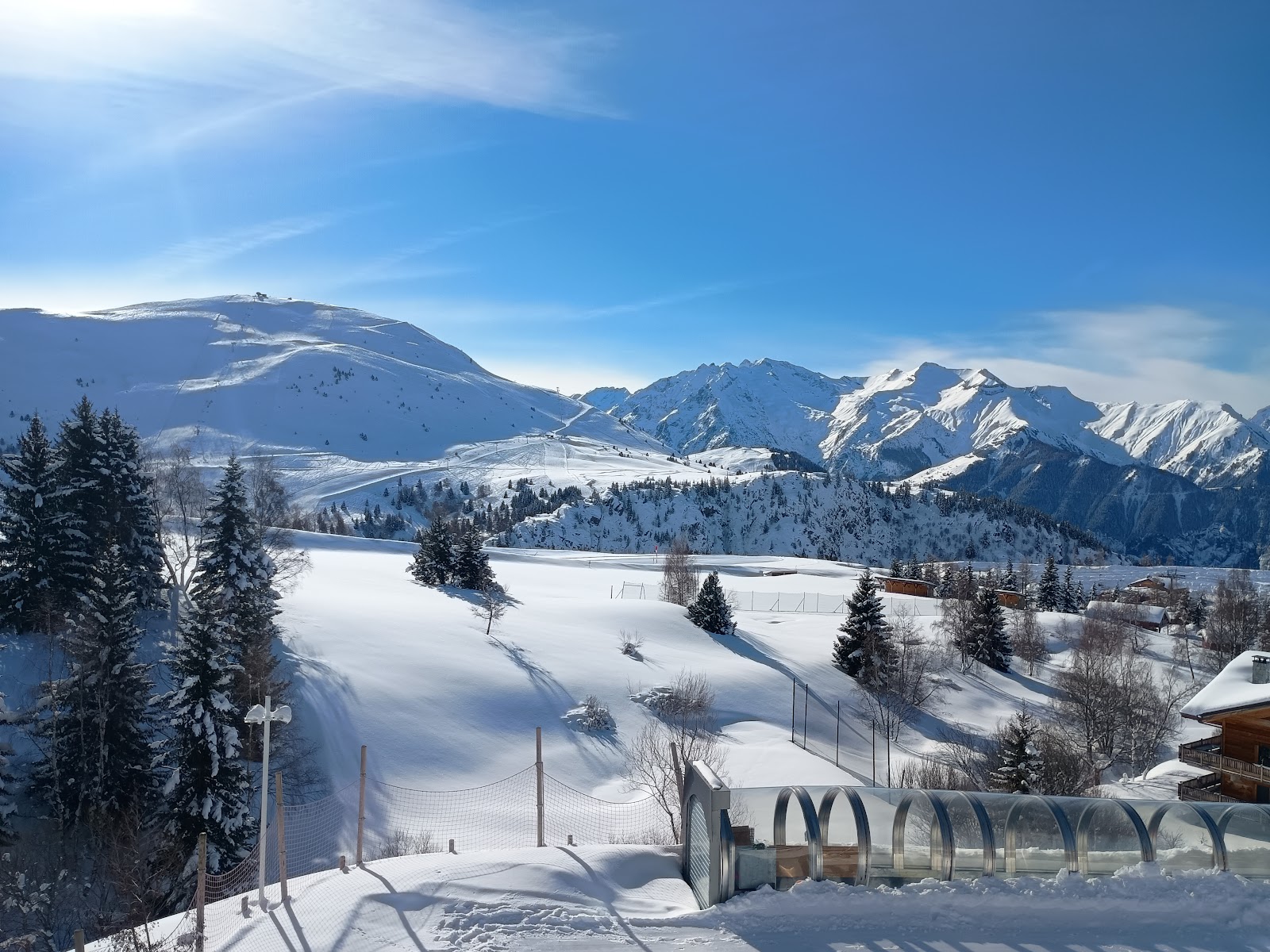 Skiers and riders on wide sunlit pistes above Alpe d Huez