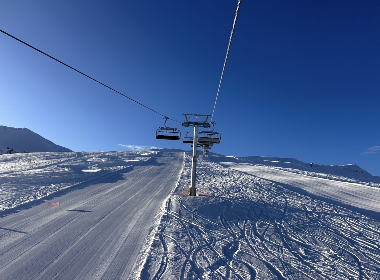 Skiers cruising a sunny groomed red run in the Maritime Alps