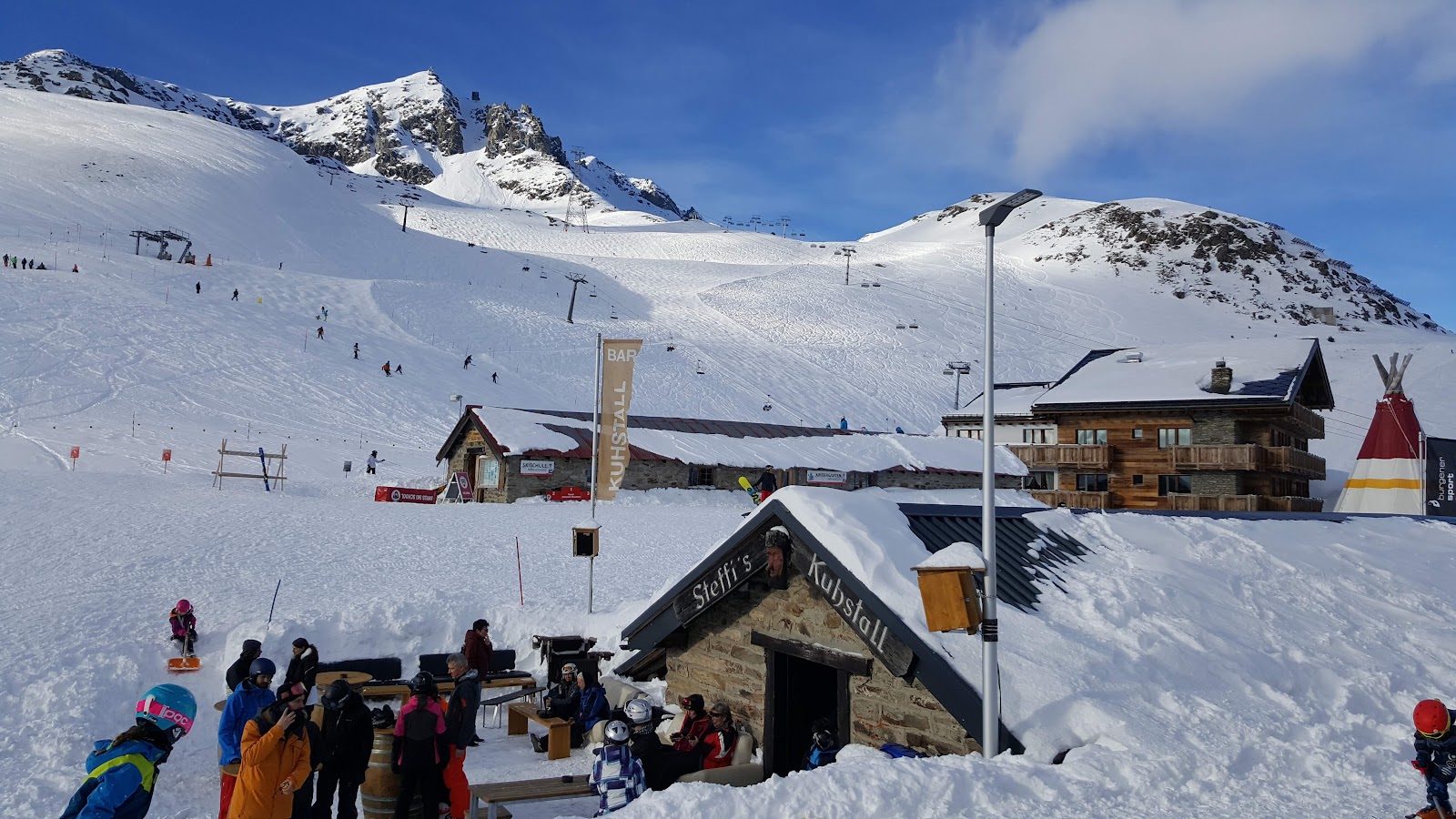 Skiers on a wide sunny groomed run in the Aletsch Arena