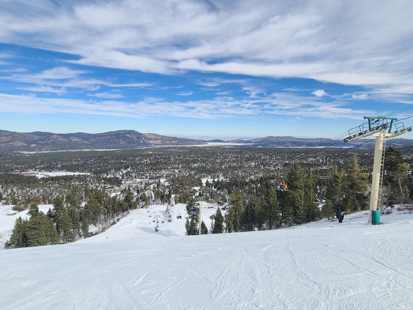 A chairlift in sunshine above Big Bear with night skiing lights