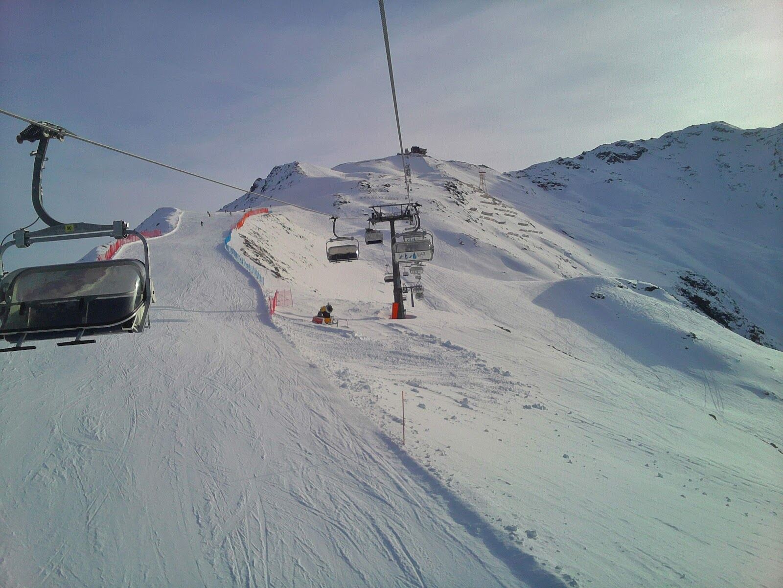 A long steep red piste descending toward the town of Bormio