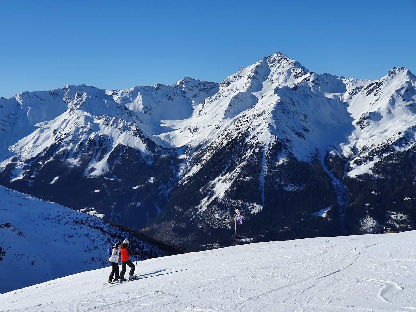 Skiers on the high Cima Bianca slopes above Bormio in sun