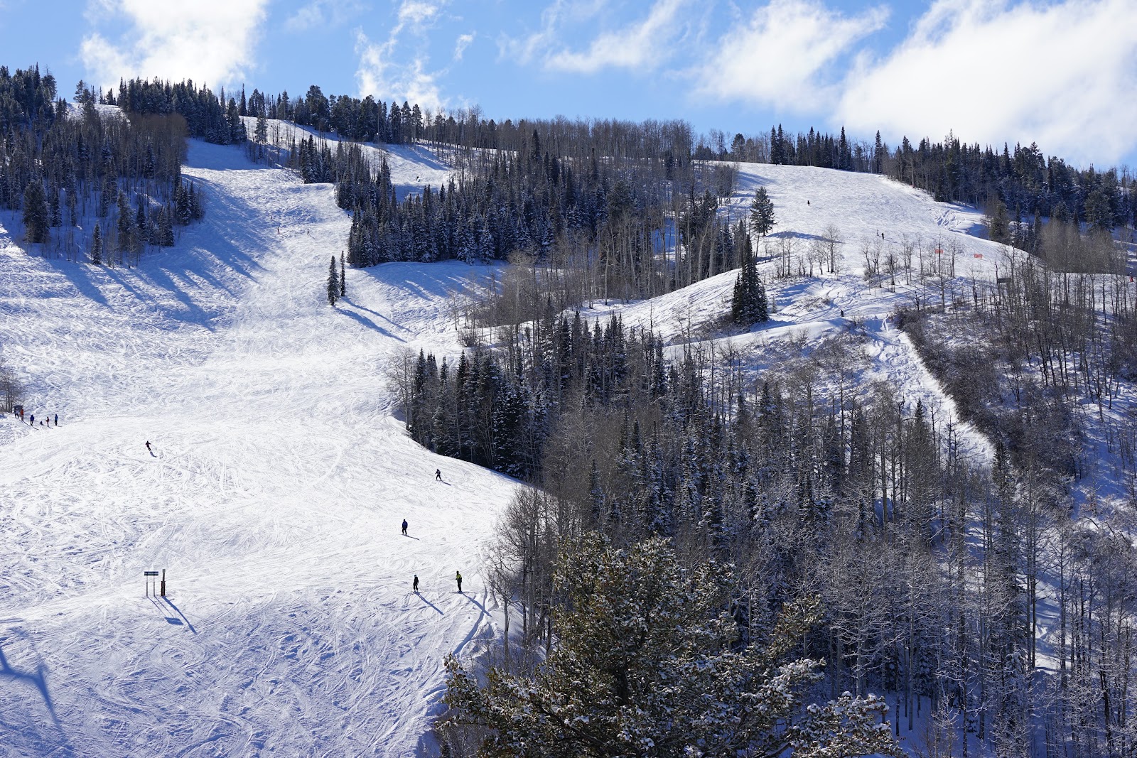 A wide groomed beginner run under blue sky at Buttermilk