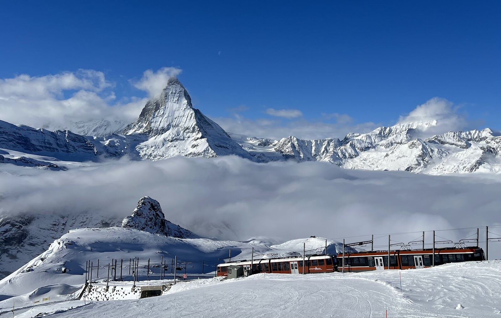 A long wide blue piste descending toward Cervinia in bright sun