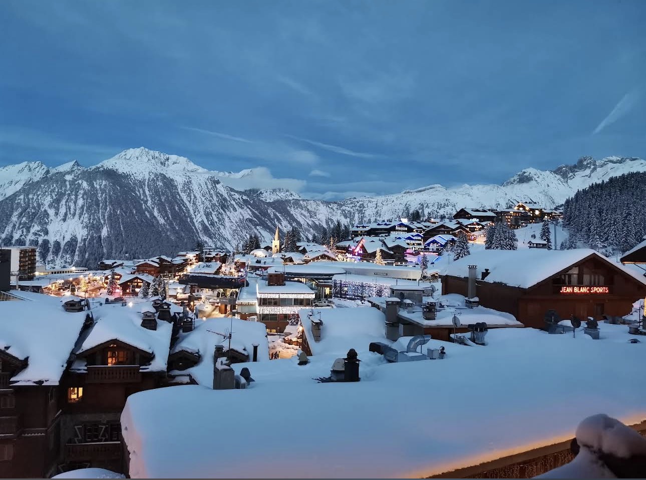 A sunny mountain restaurant terrace with diners above the snow