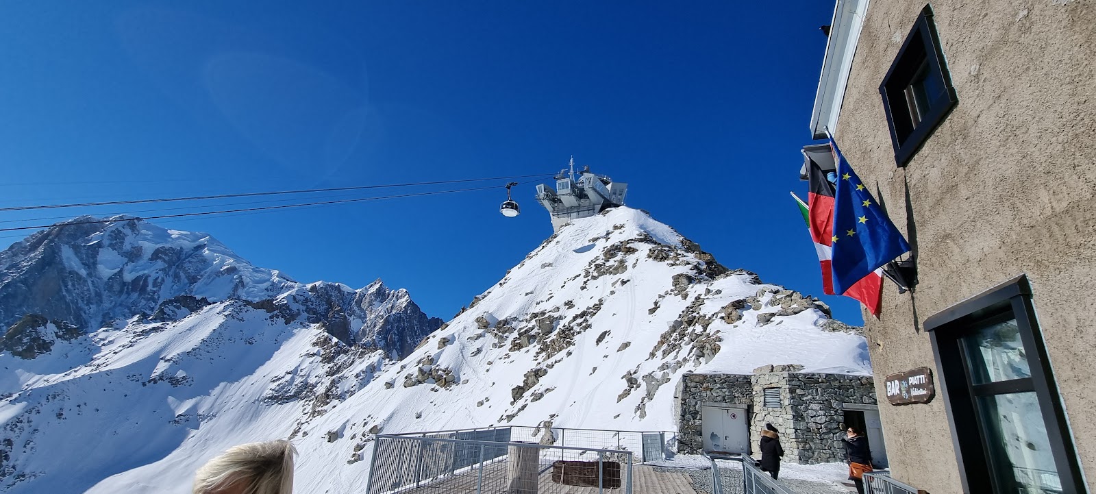 Skiers on a sunny groomed red run above Courmayeur with Mont Blanc behind