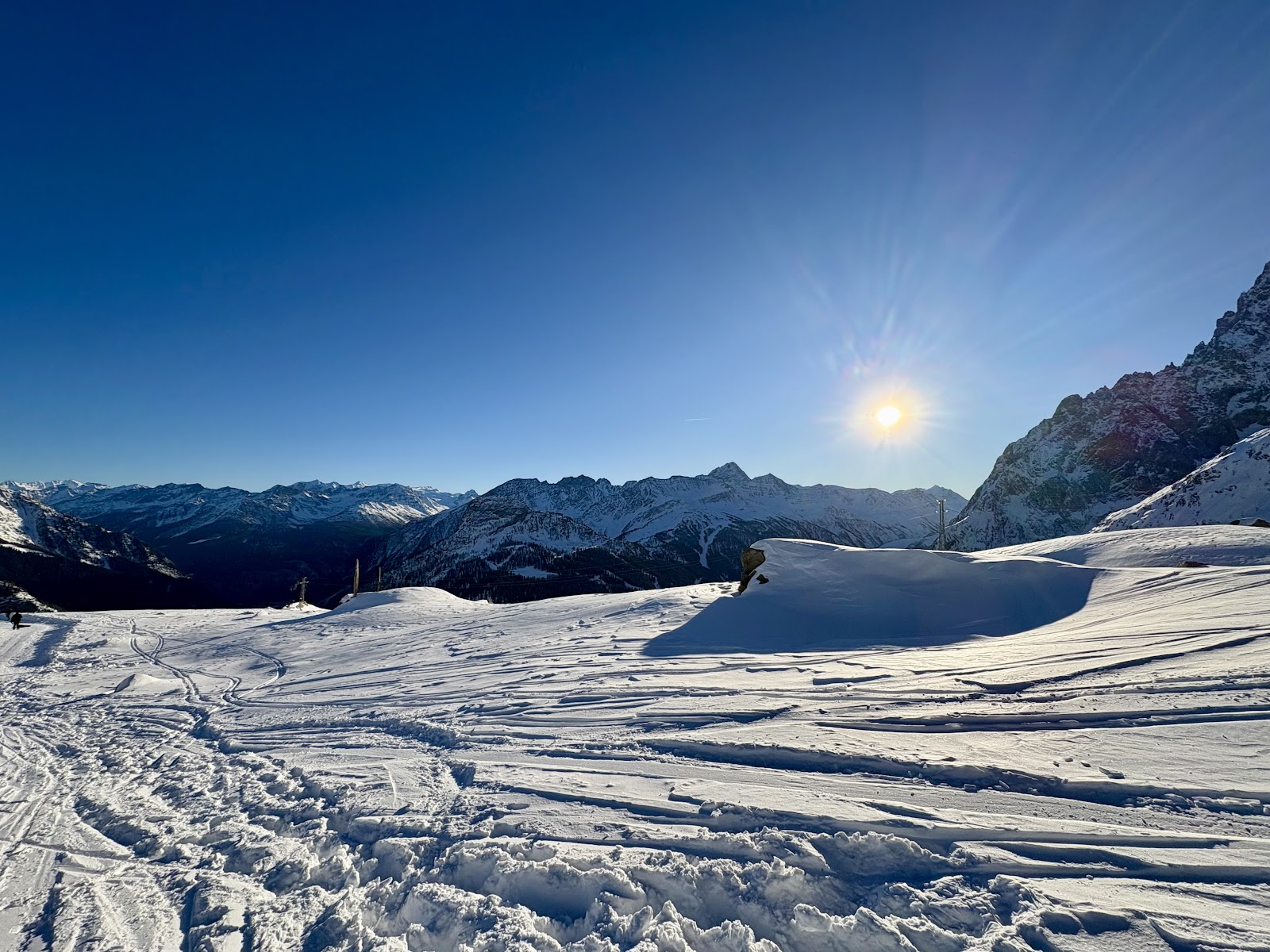 A busy mountain restaurant terrace above Courmayeur with skiers eating in the sun