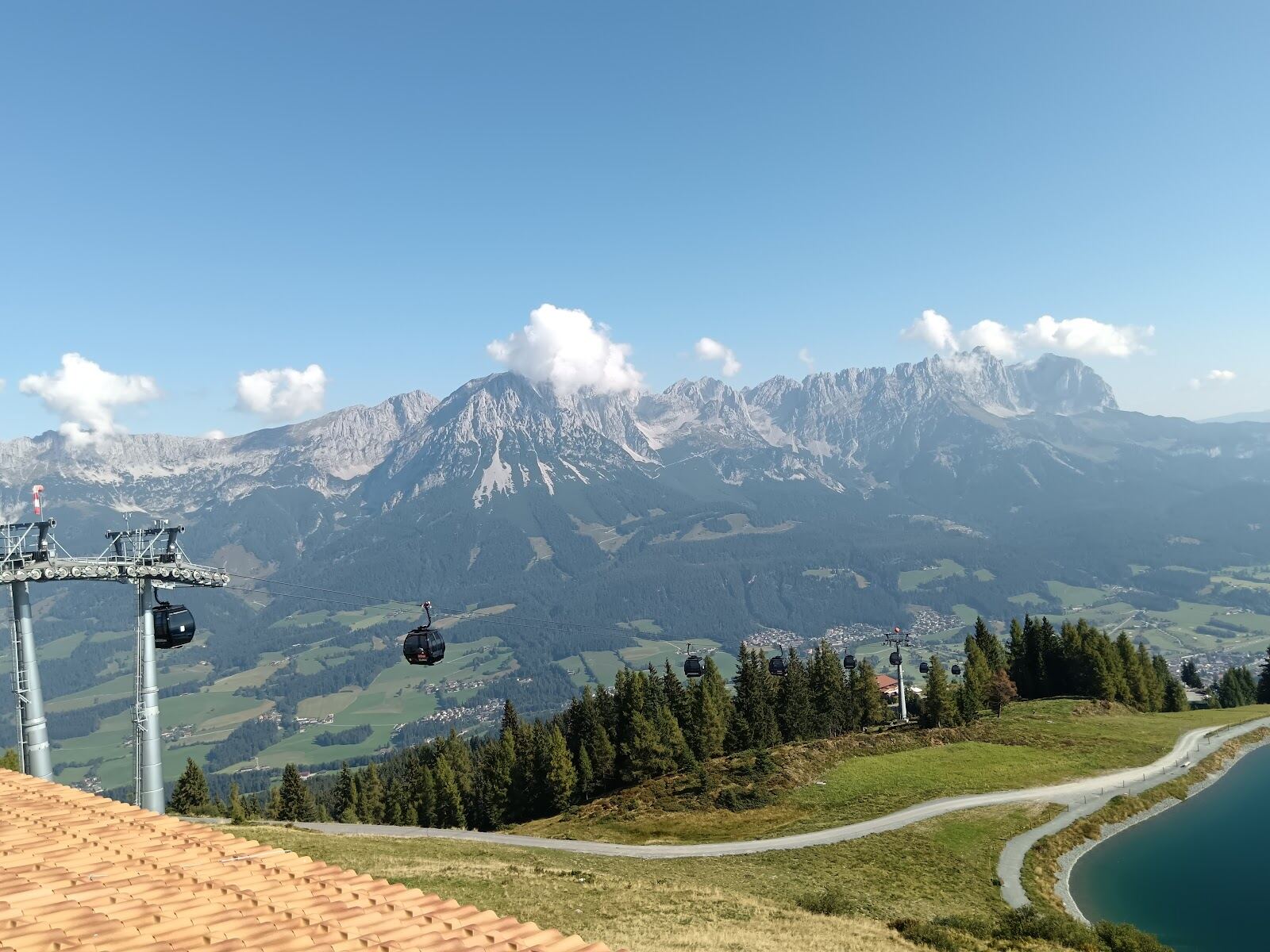 Skiers cruising a sunny blue run with the Wilder Kaiser beyond