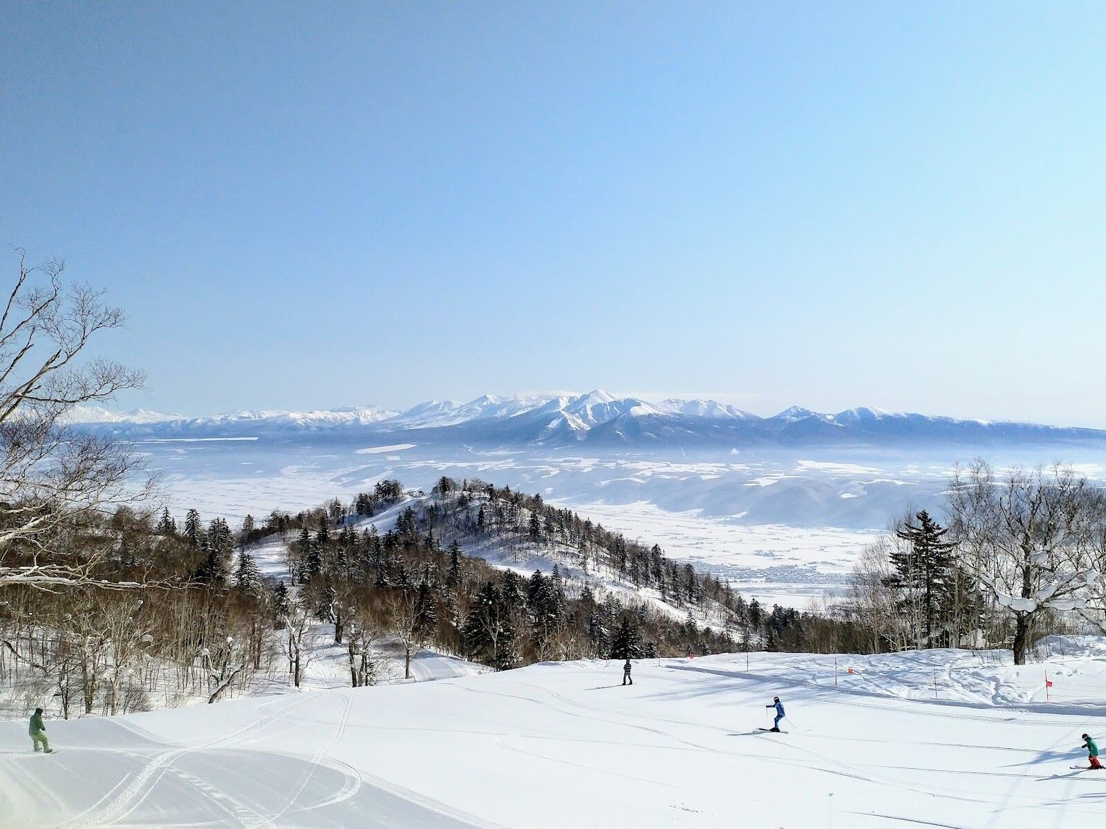 A wide groomed piste under grey winter sky at Furano