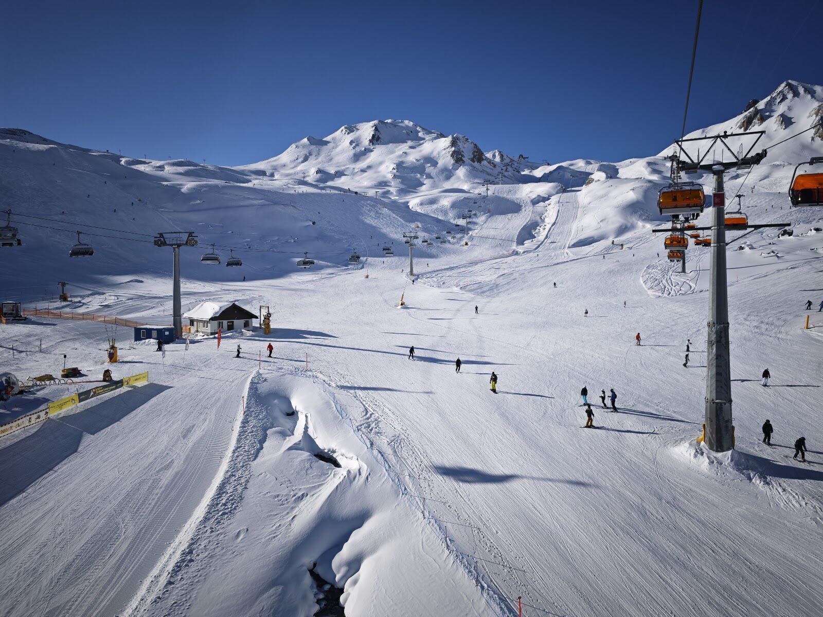 Skiers on a wide well groomed piste in the high Silvretta Arena above Ischgl