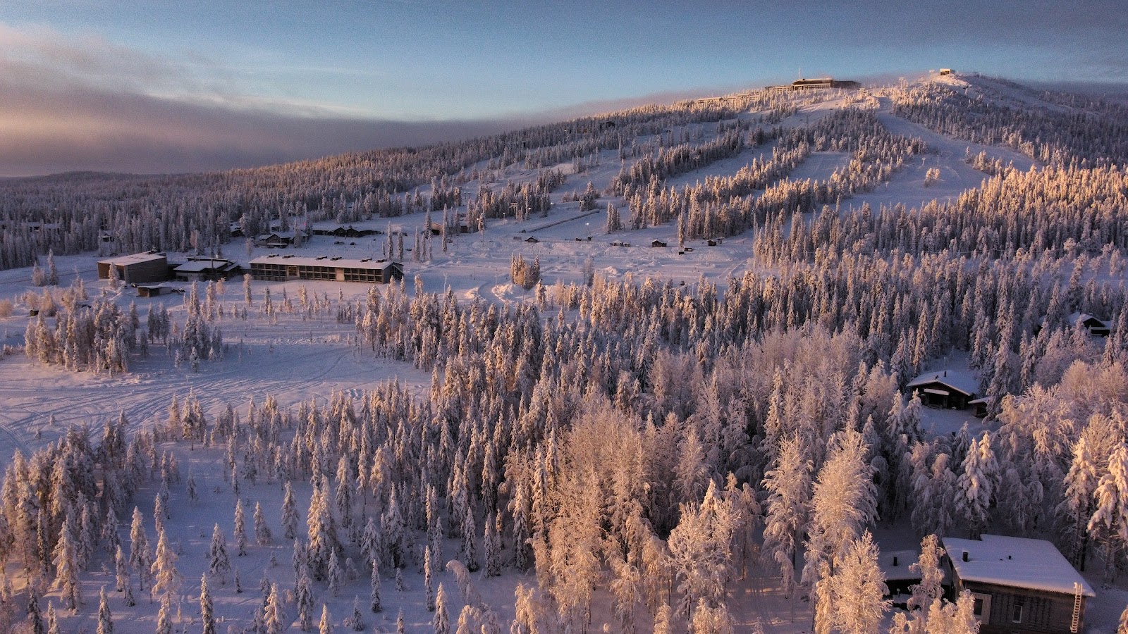 Snow covered fell top and log cabins at Iso Syote under an Arctic sky