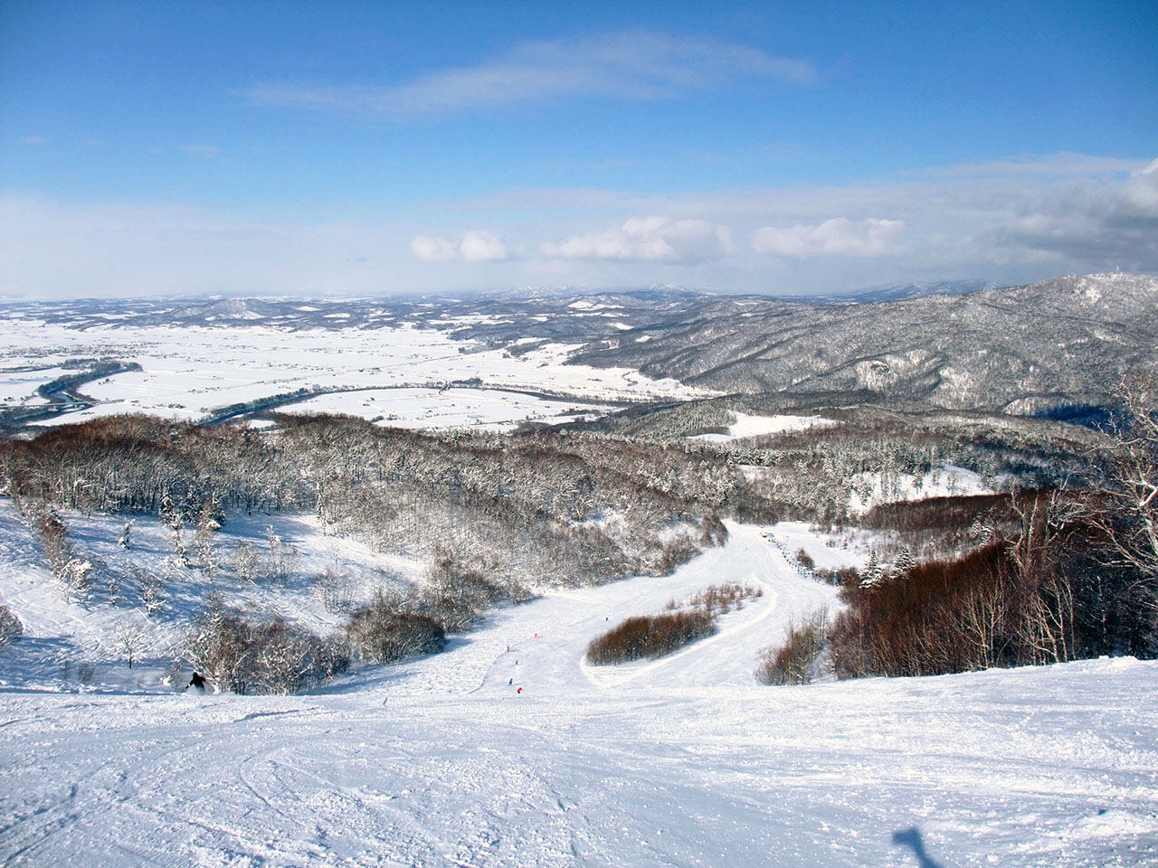 Skiers riding fresh snow under a gondola at Kamui Ski Links near Asahikawa