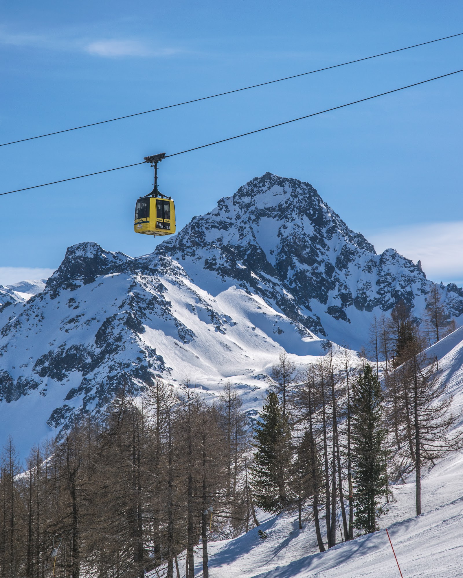 Empty snowy pistes above La Thuile in Italy with the cross border link to La Rosiere behind