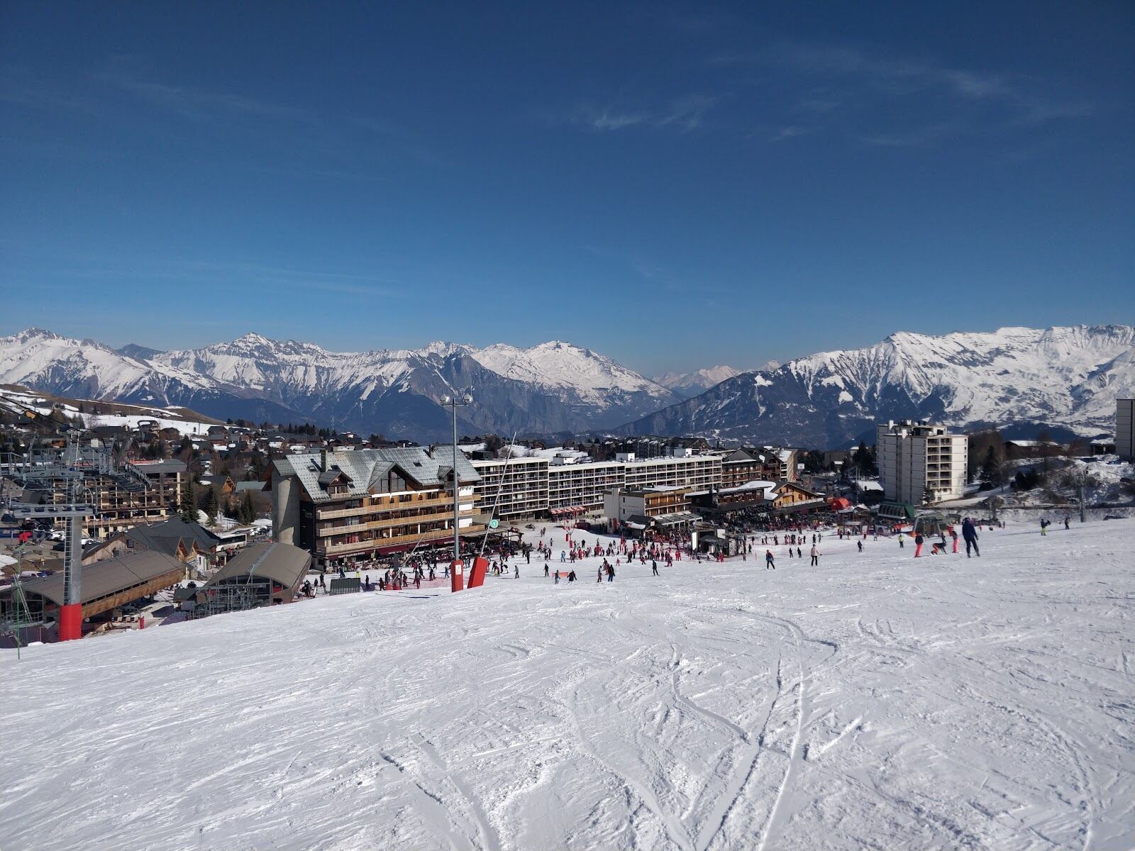 Skiers cruising a wide gentle piste in Les Sybelles above La Toussuire