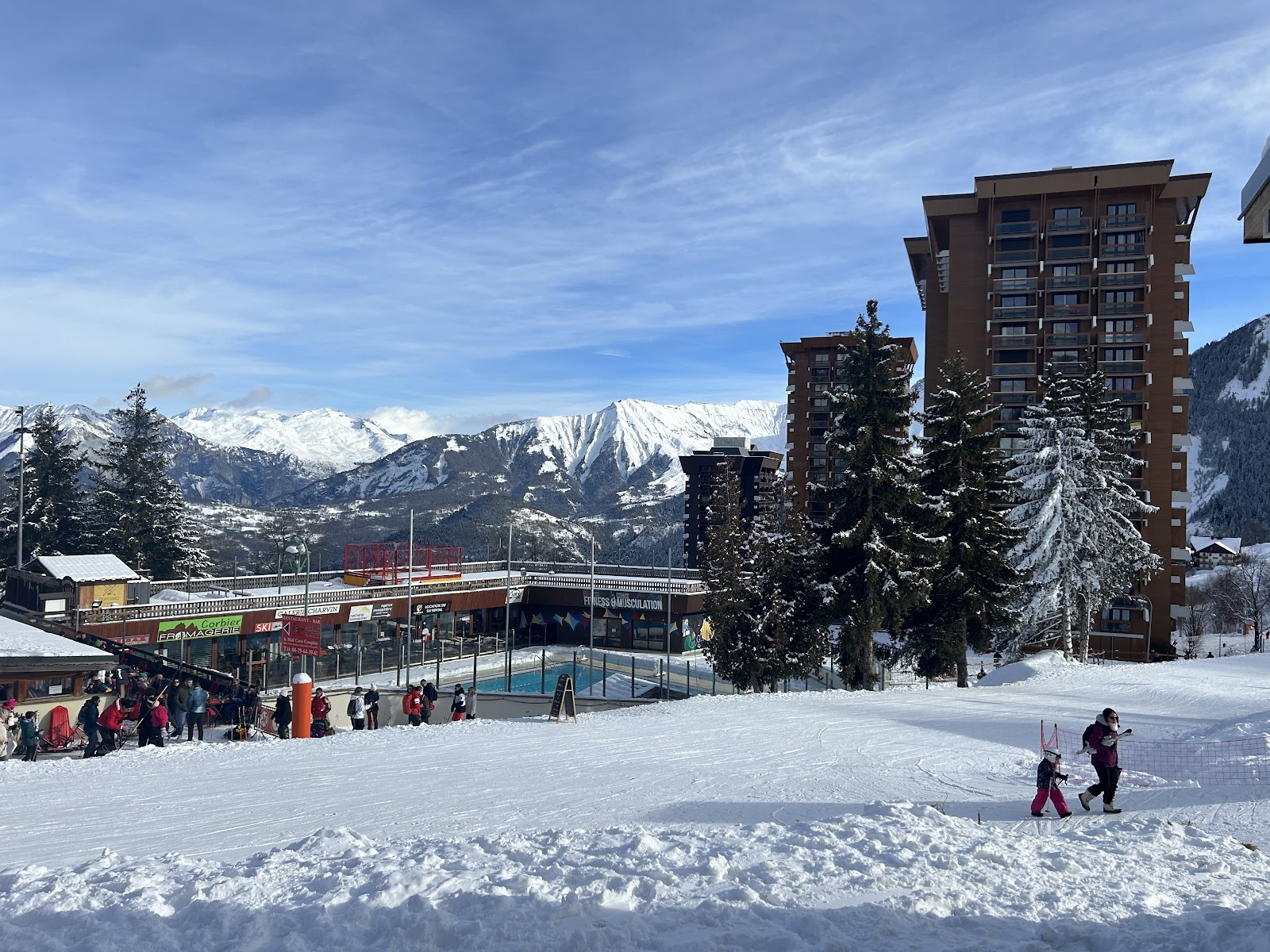 Skiers cruising open intermediate slopes in Les Sybelles
