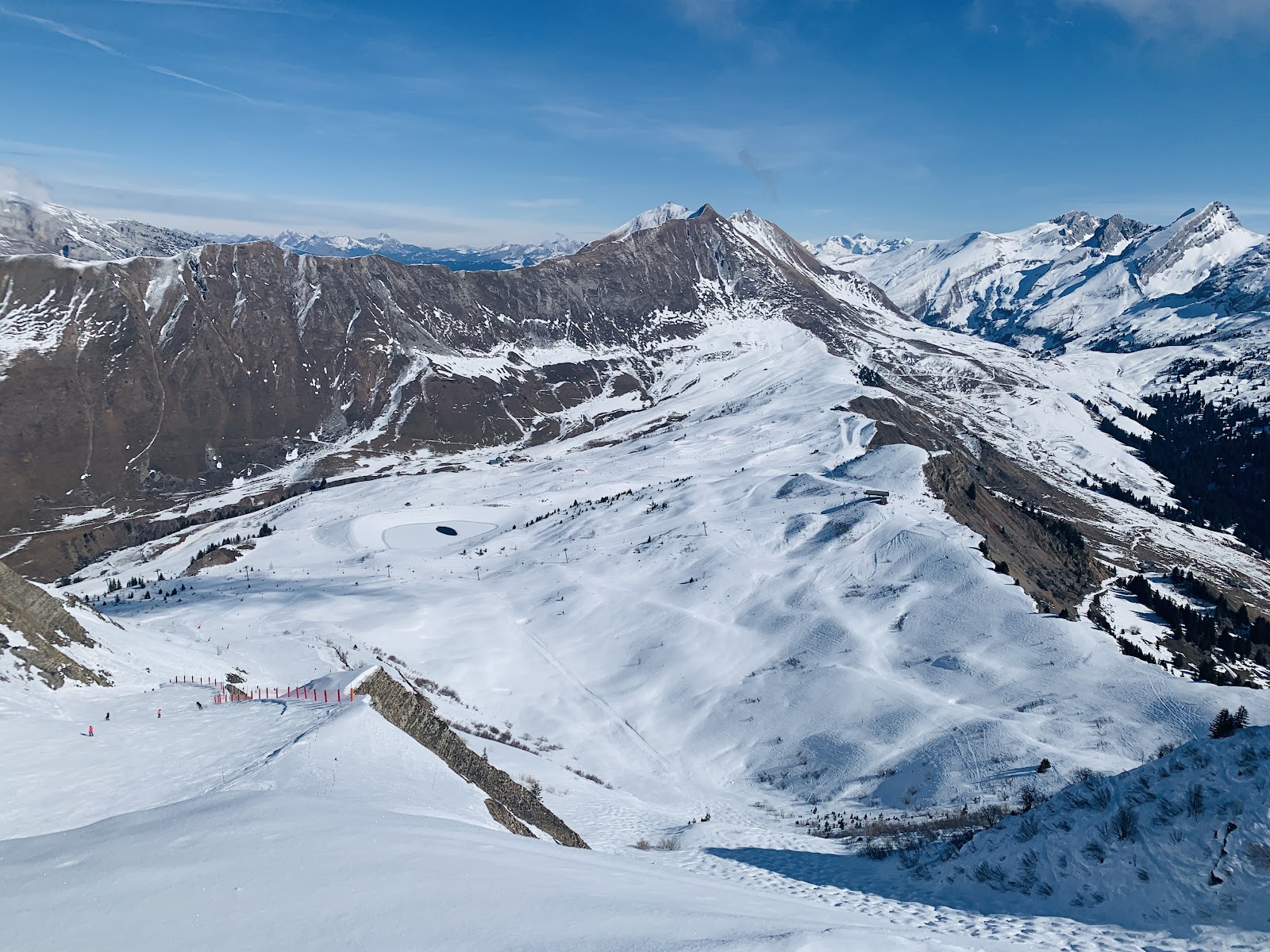 Skiers on a sunny groomed run above Le Chinaillon