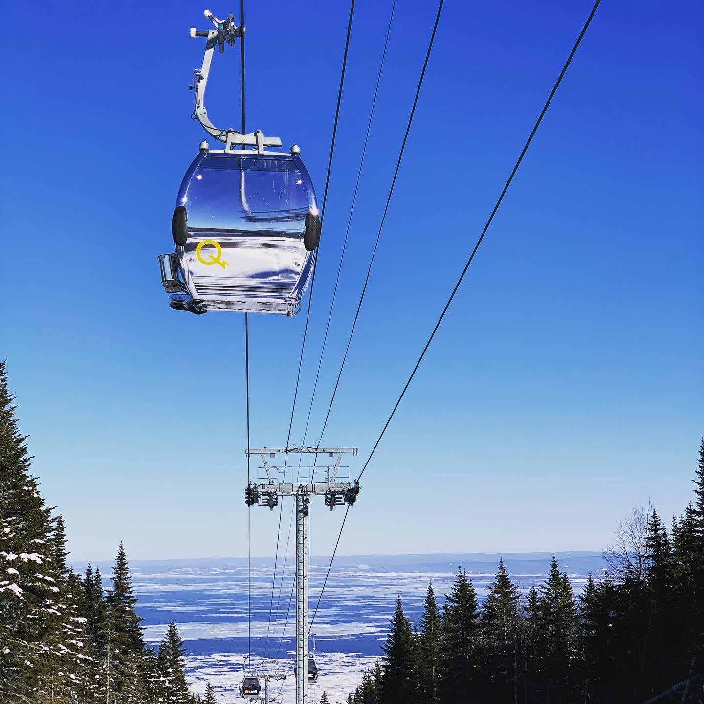 Ski runs at Le Massif dropping toward the wide St Lawrence River in Quebec