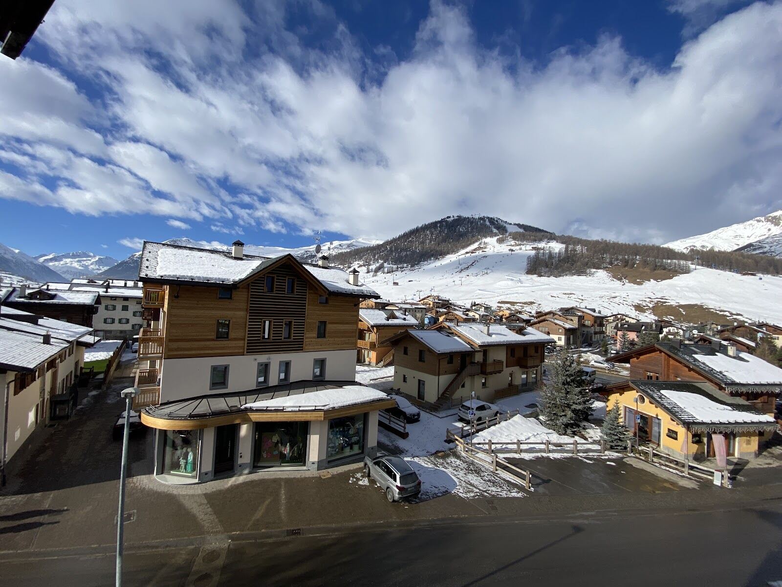 Skiers on a wide blue piste above Livigno with reliable snow