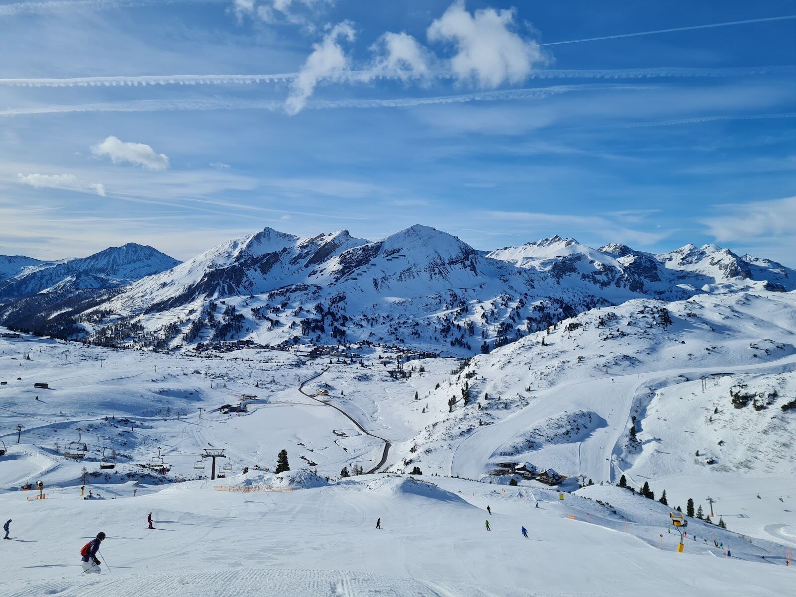 Skiers on a wide red piste on the circuit around Obertauern