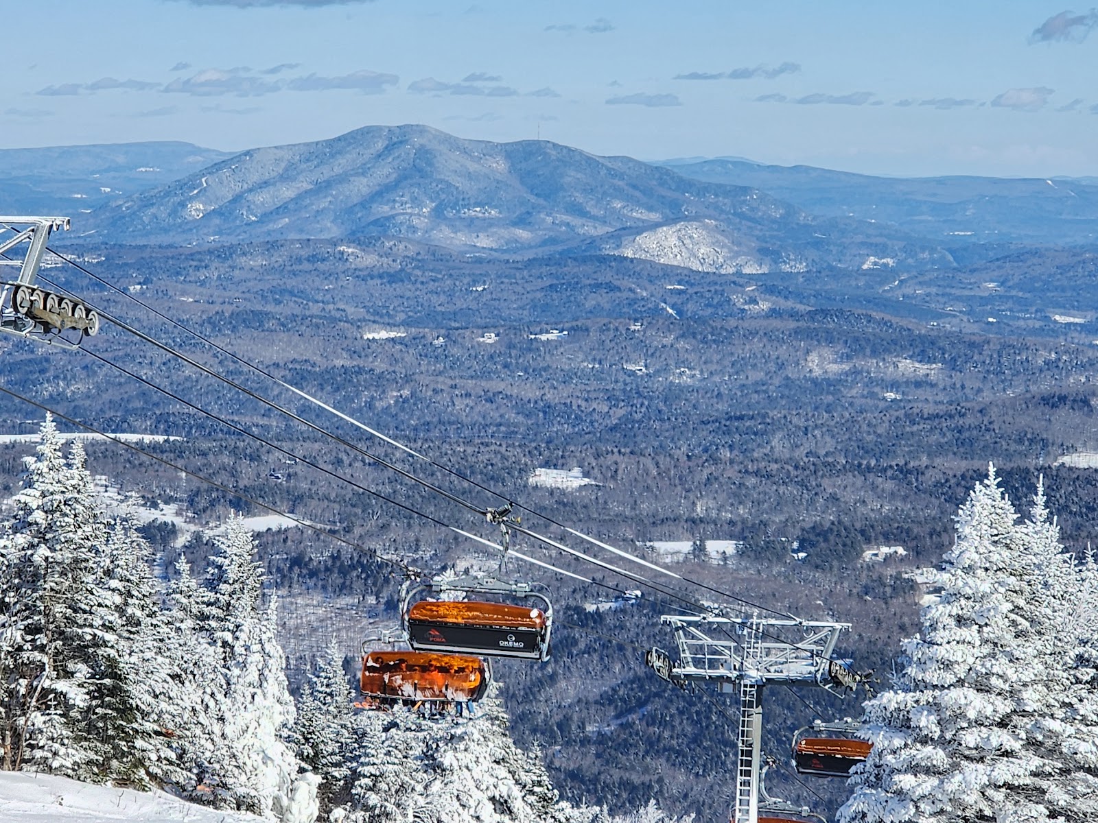 Fast chairlift rising over snowy slopes at Okemo