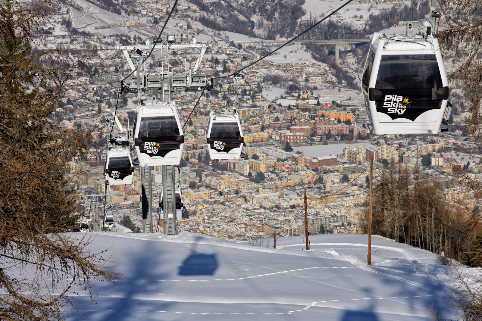 Sunny pistes at Pila above the Aosta Valley with high alpine peaks beyond