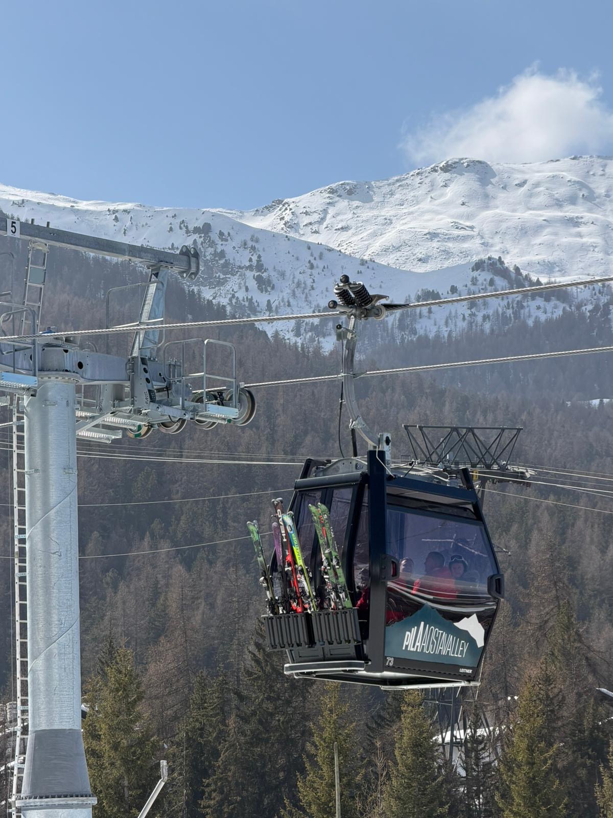 Skiers carving a groomed run with high alpine peaks in the distance
