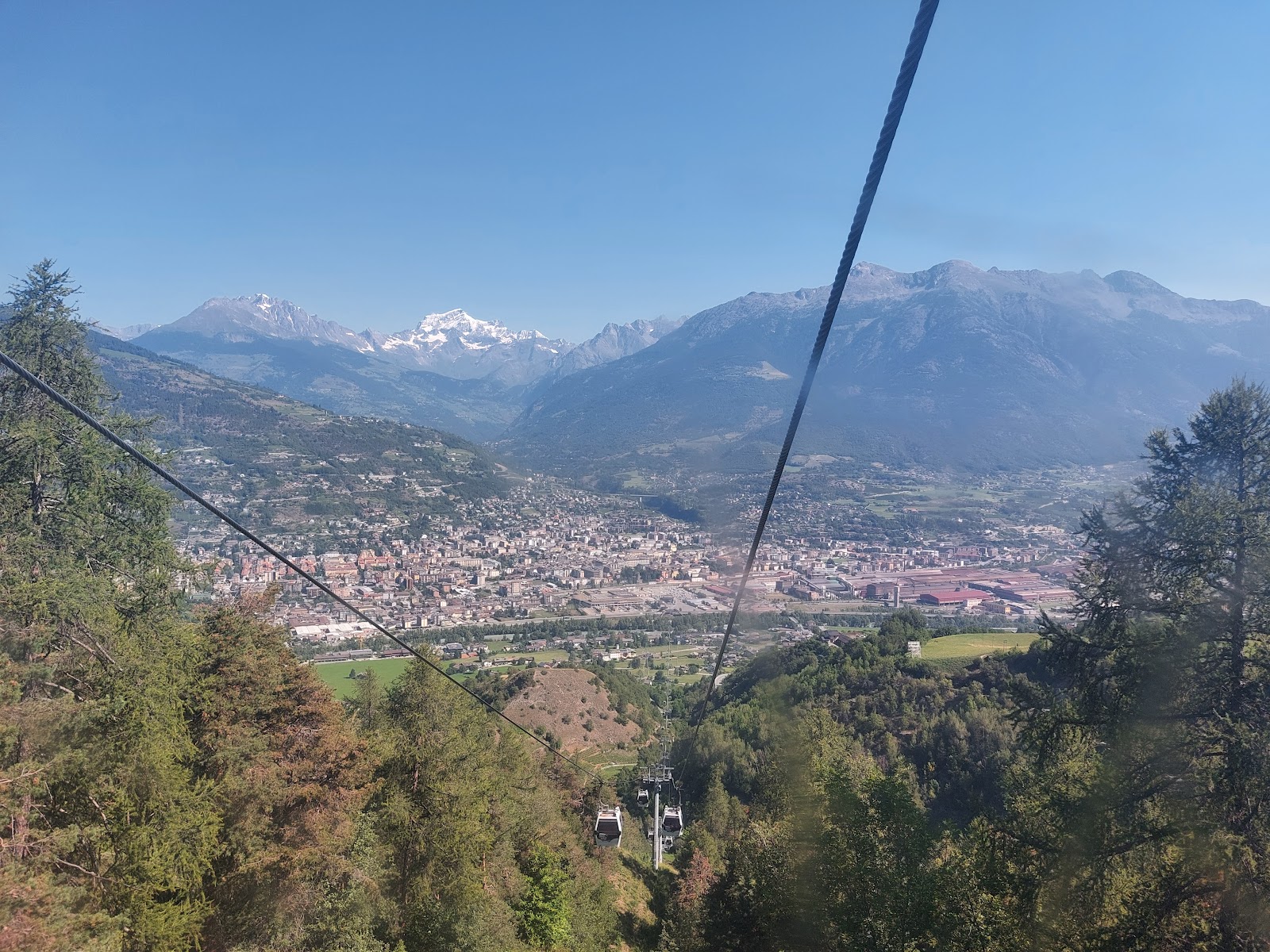 A chairlift rising over a tree lined sunny slope at Pila