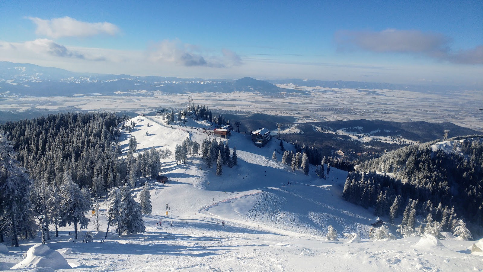Snowy pistes of Poiana Brasov below the wooded Postavarul ridge