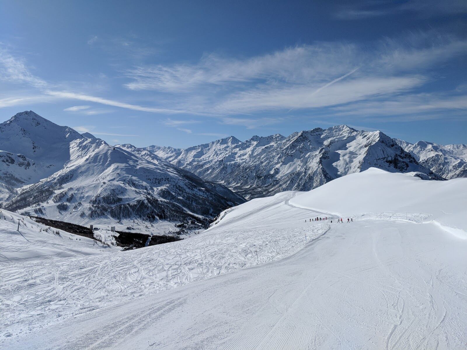 Skiers cruising a wide sunny piste on the Milky Way circuit
