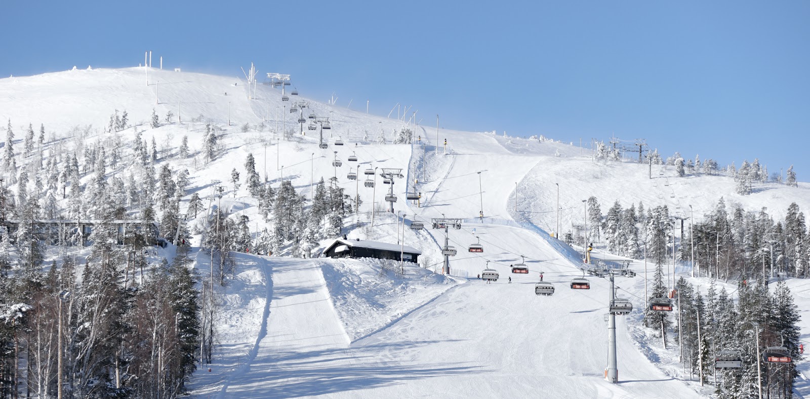 Snow covered fell and floodlit pistes at Pyha ski resort in Finnish Lapland under a dark sky