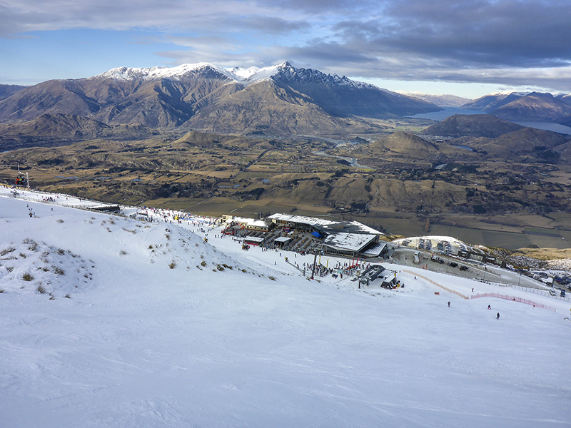 Skiers at Coronet Peak with the Wakatipu basin and mountains behind