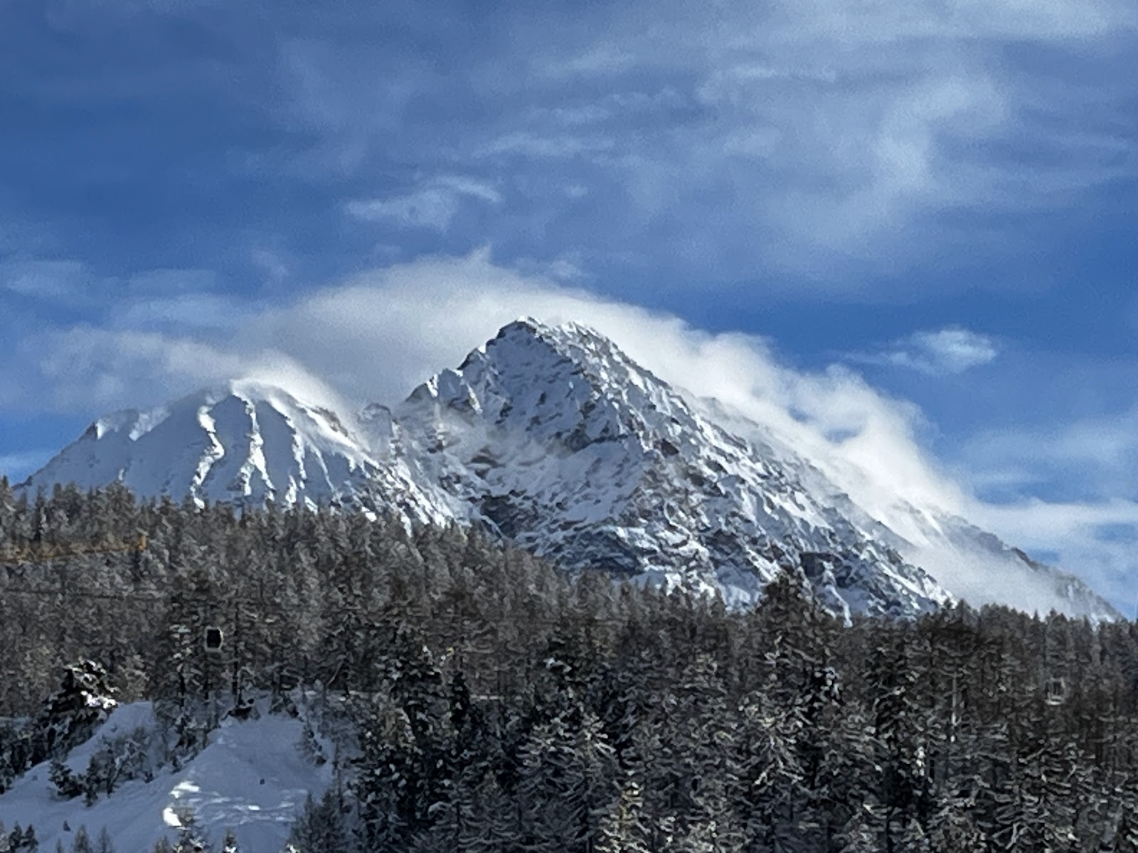 Skiers cruising a long sunny groomed run on the Via Lattea