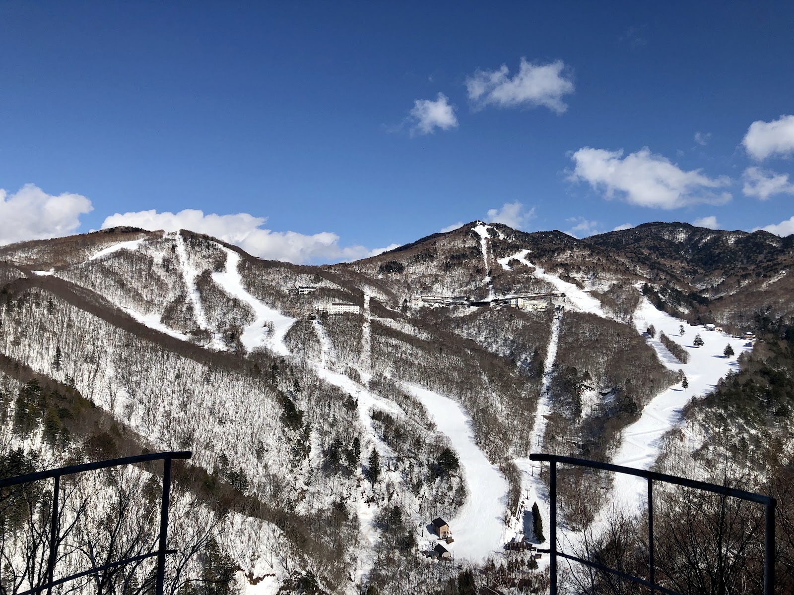 Skiers riding an old chairlift across a wide white bowl