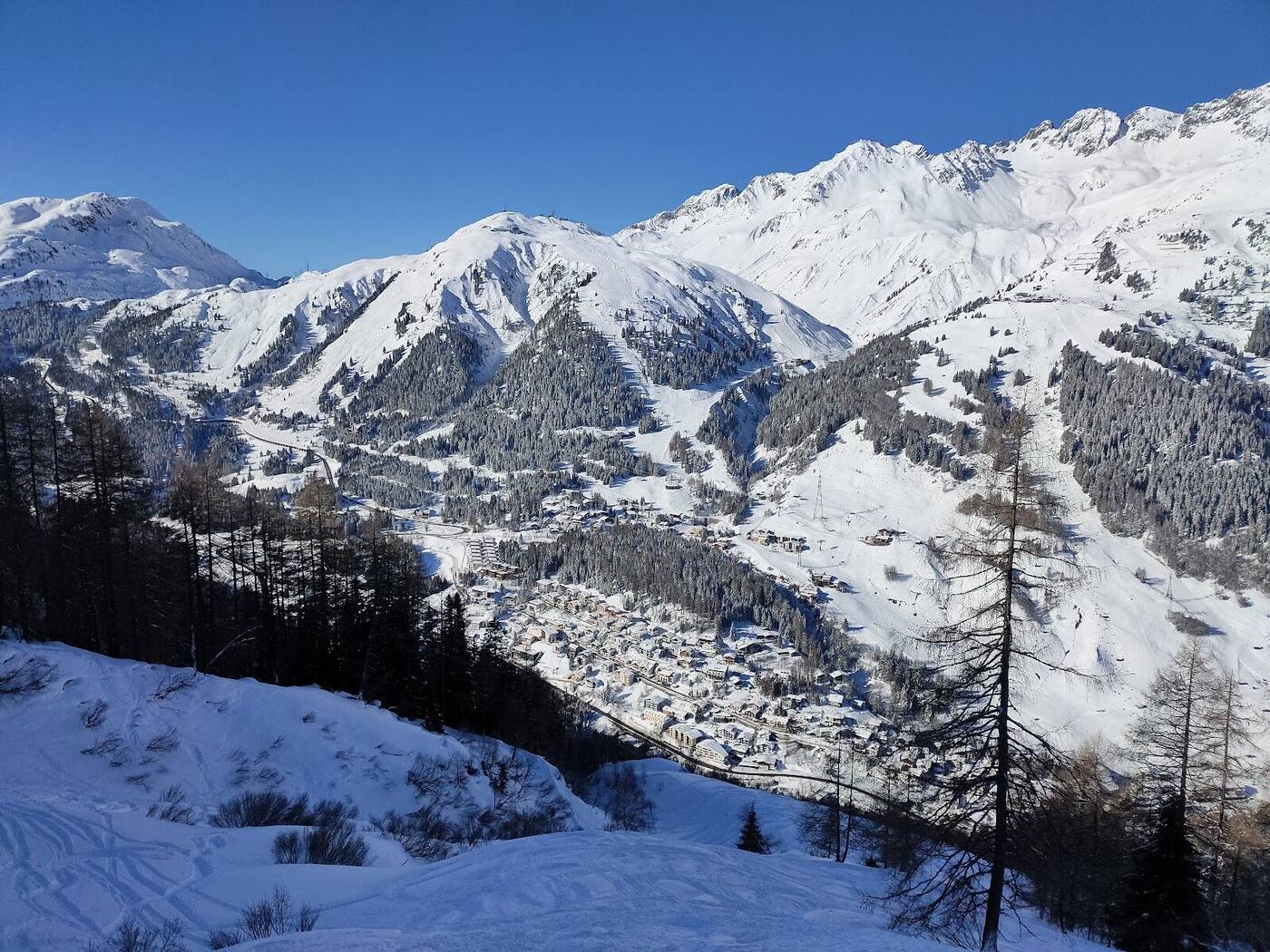 Skiers riding a high lift over open Arlberg terrain