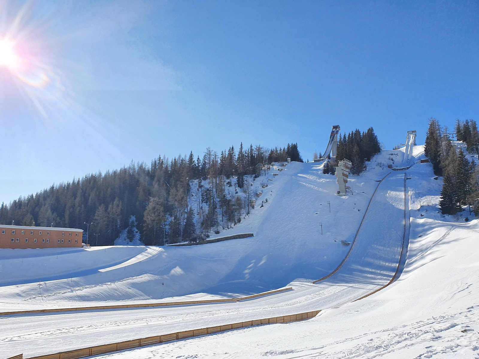 A chairlift rising toward Solisko above snowy spruce forest