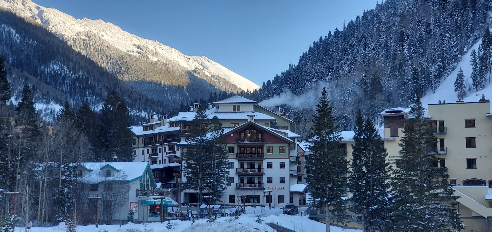 A steep snow covered mountain face rising above a southwestern ski valley at Taos