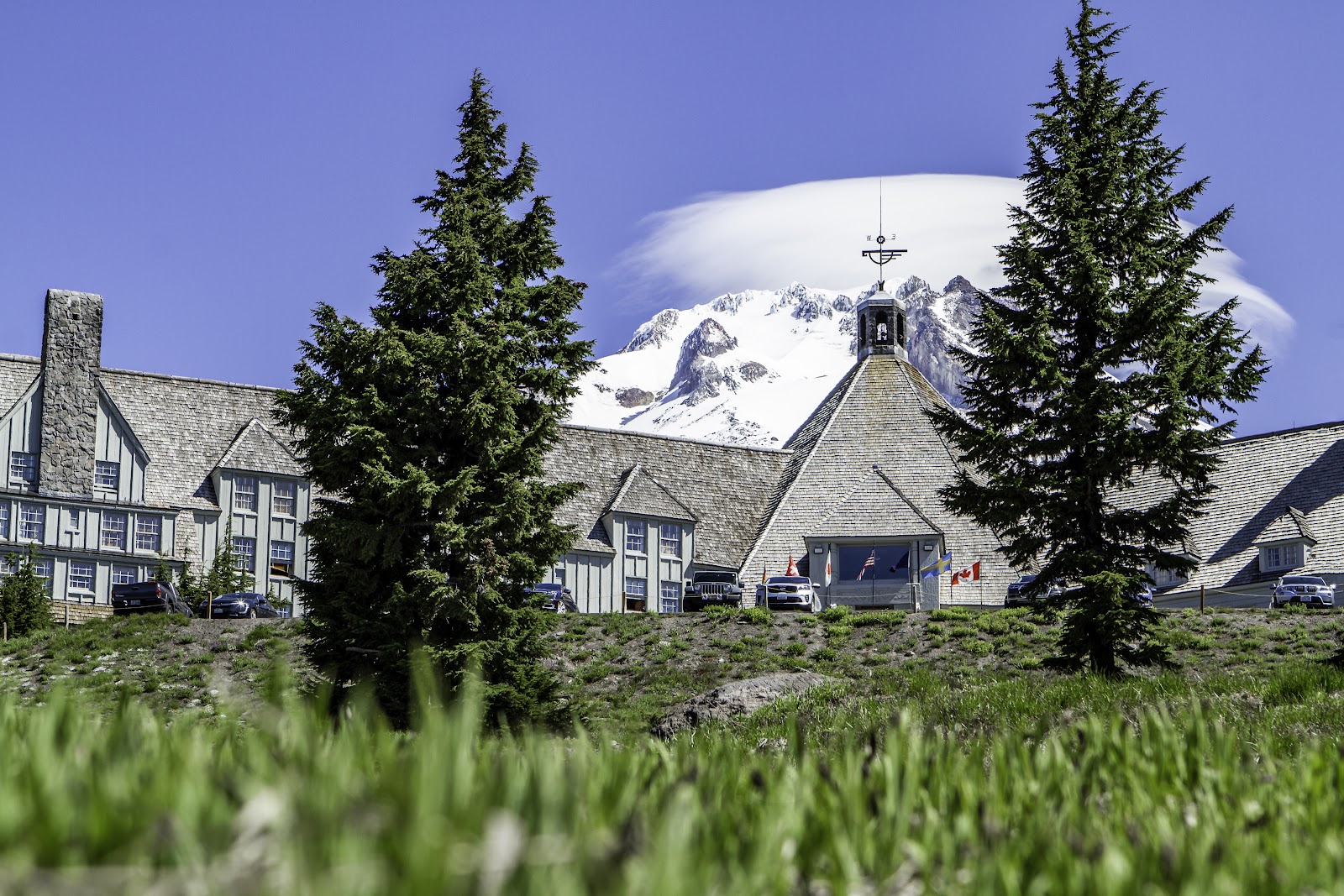 Historic timber and stone mountain lodge below a snowy volcanic peak