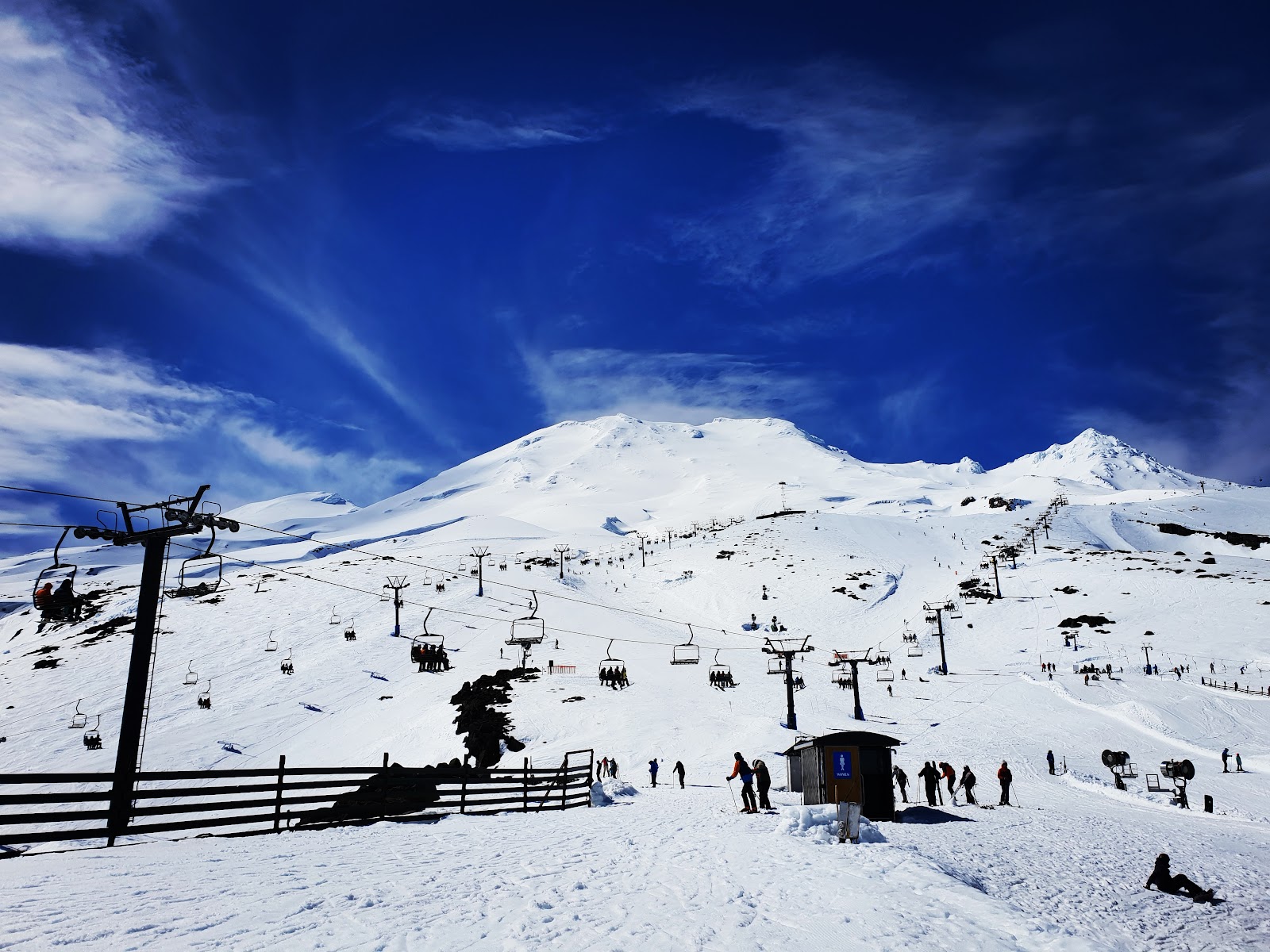 A chairlift rising over treeless lava and snow on the volcano