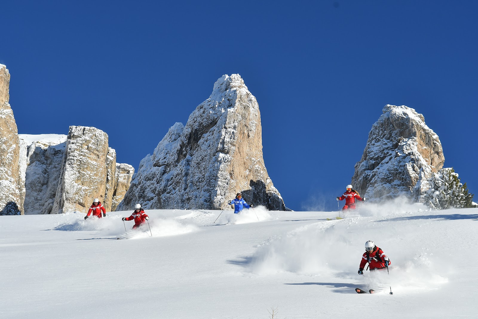 Skiers cruising a wide red run on the Sella Ronda circuit