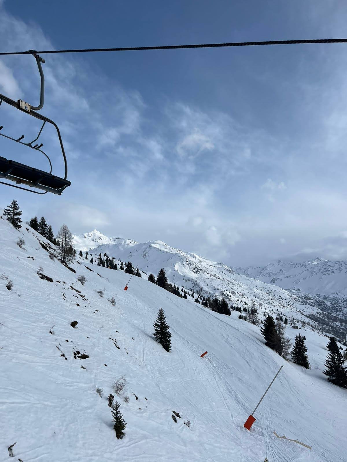 Skiers on a sunny open run above Valmeinier