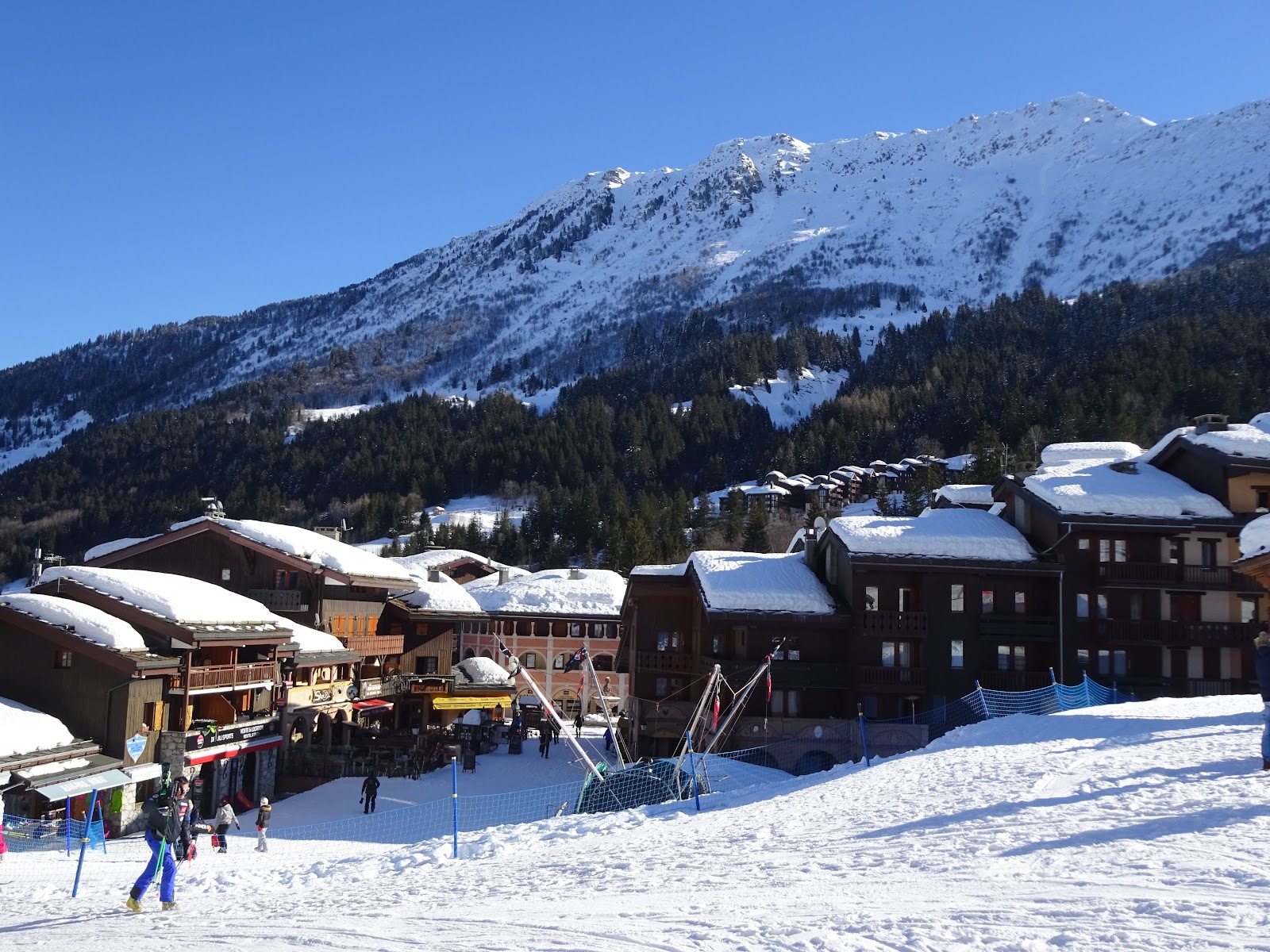The car free village street of Valmorel lined with timber and stone chalets under snow