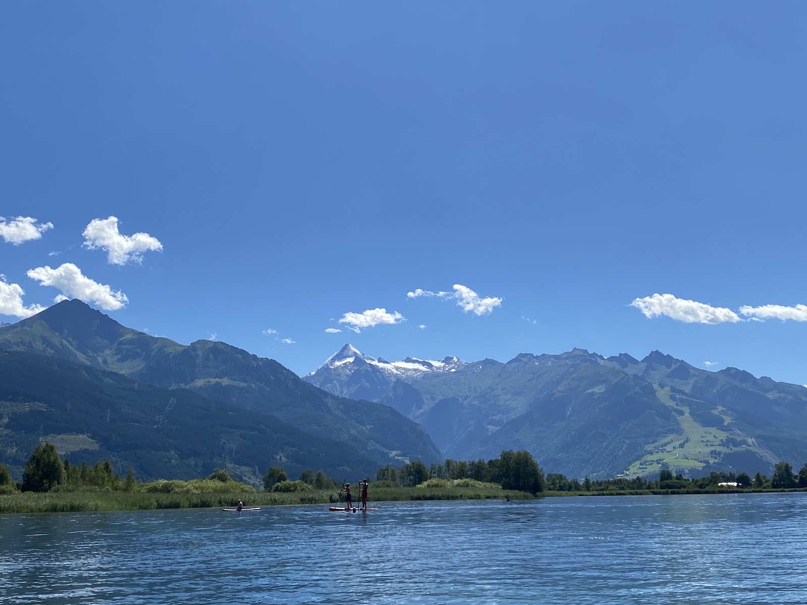 Ski pistes above the blue lake at Zell am See with mountains beyond