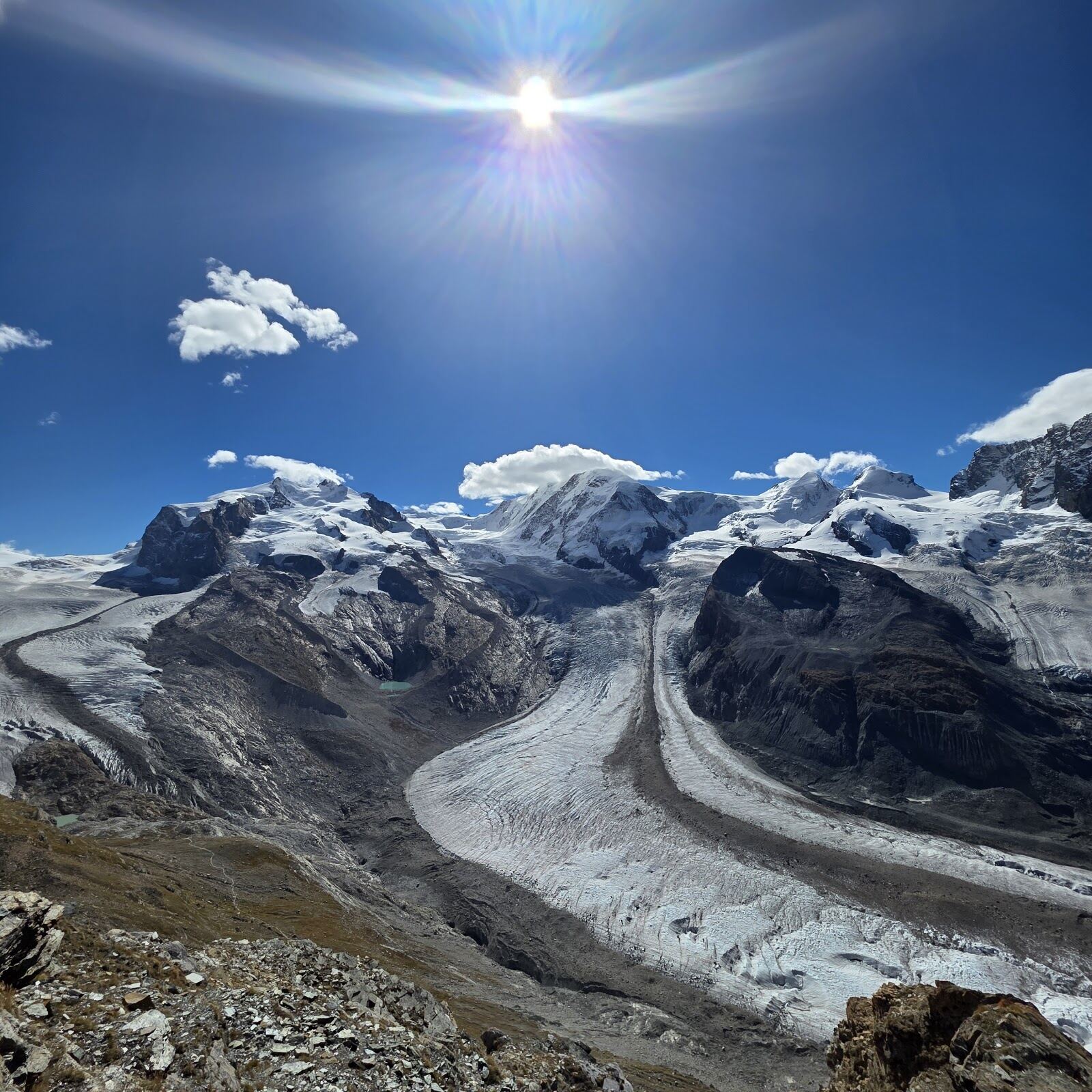A wide groomed red run high above Zermatt in winter sun